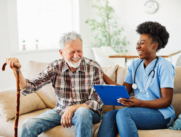 Doctor or nurse caregiver with senior man at home or nursing home